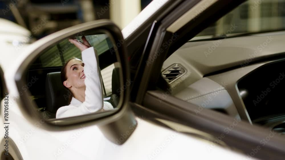 Satisfied happy caucasian female client customer woman sitting at the wheel of new car doing test-drive before buying auto while male shop assistant helping her choose it Satisfied happy caucasian female client customer woman sitting at the wheel of new car doing test-drive before buying auto while male shop assistant helping her choose it