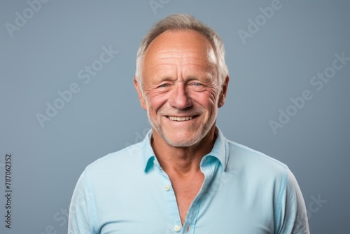 Portrait of a grinning man in his 50s donning a classy polo shirt isolated on pastel gray background