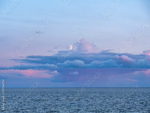 First quarter moon and rain clouds at dusk over Kattegat from Tuno island, Midtjylland, Denmark