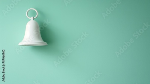 A white ceramic bell with a simple, sleek design hangs against a soft green background, offering a tranquil and minimalist aesthetic.