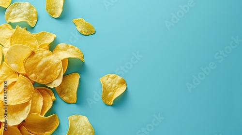 Scattered many fried potato chips on blue background. Space for text. Top view