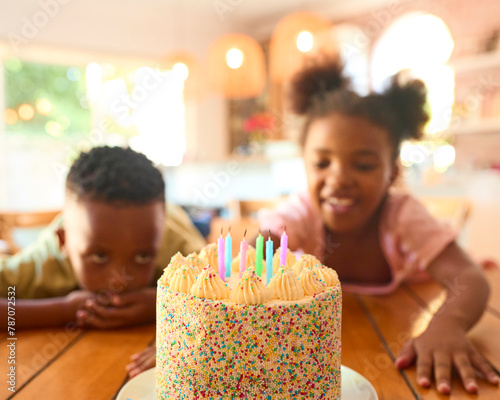 Two Children Looking Hungrily At Tasty Birthday Cake On Table For Party photo