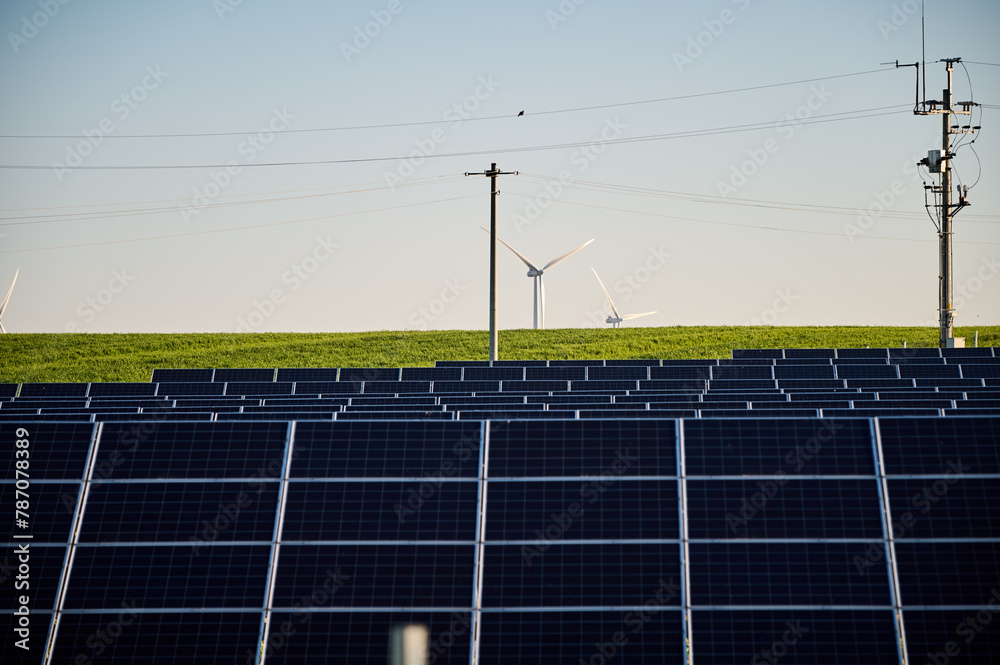 Φωτογραφία Solar panels against the background of a field with electricity pylons and wind farms beyond the horizon