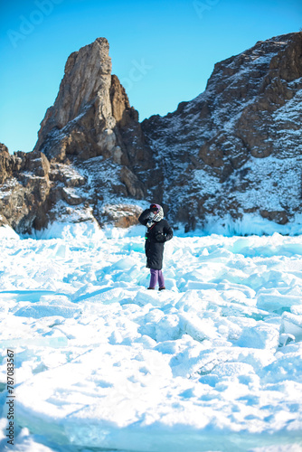 Woman tourist photographer ioutdoors, standing at frozen surface of lake Baikal photo