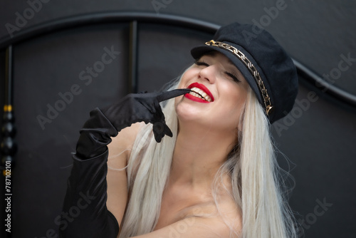 Beautiful blonde sexy mannequin wearing a hat and red lips. Sexy blonde model with hat in bed on black background.