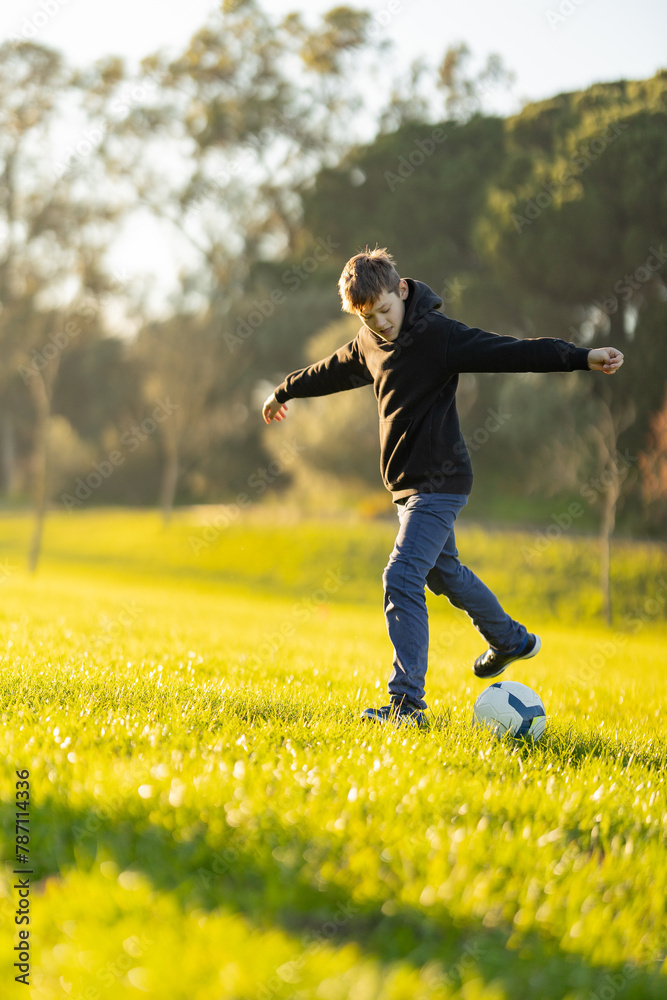 A boy is playing soccer in a field