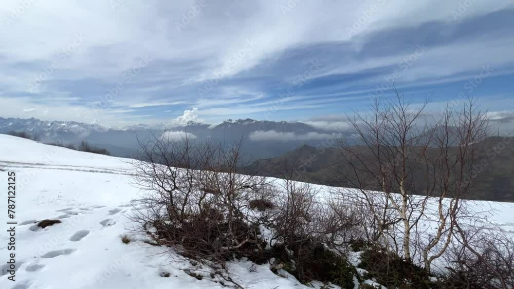 Archonsky Pass. The pass connects the Kurtatinsky gorge with the Alagirsky. Alanya, view of the mountains of the North Caucasus, peaks covered with snow. Sunny day, blue sky with a slight haze. 4К