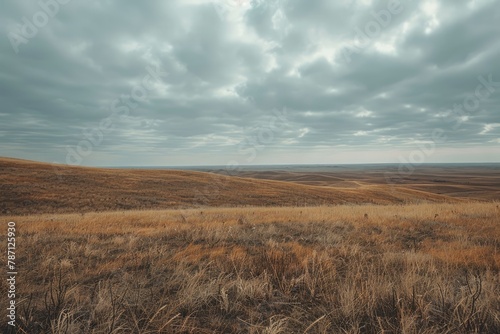 beautiful scene of brown rolling hills with white and brown mountains and a brown grass field covered with clouds in the sky in a cloudy day in the morning