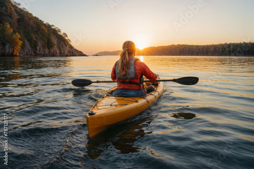 Rear view of woman paddling kayak at sunset on sea kayaking and canoeing adventure in calm waters © polack