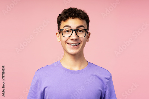 Portrait of smiling happy boy, teenager with braces wearing eyeglasses looking at camera