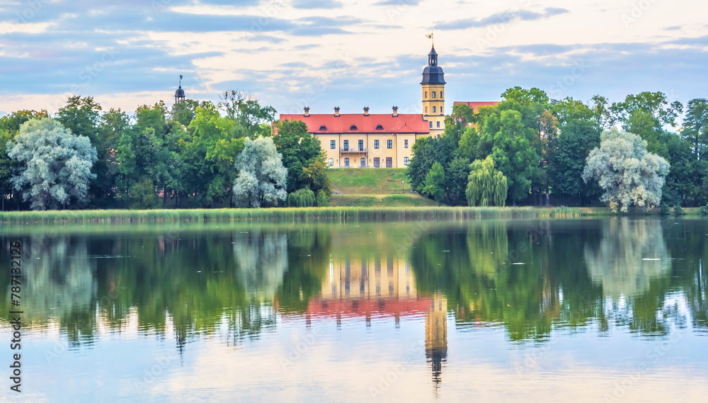 A landscape with a medieval castle on the shore of a lake and its reflection in the water