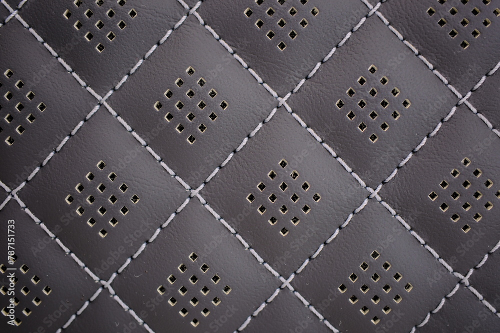 White contrast thread on perforated natural black leather car seat close-up White contrast thread on perforated natural black leather car seat close-up