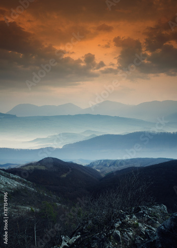 colorful sunset landscape with mountains in mist
