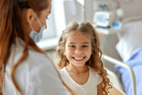 A young girl smiles as a nurse checks her temperature, medical equipment in a hospital room.