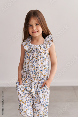 Beautiful little girl with long hair, wearing a colorful spring dress in flowers
