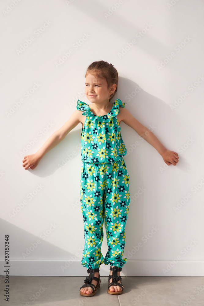 Beautiful little girl with long hair, wearing a colorful spring dress in flowers Beautiful little girl with long hair, wearing a colorful spring dress in flowers