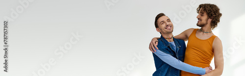 good looking joyous lgbtq friends in vibrant clothes hugging on gray backdrop, pride month, banner photo