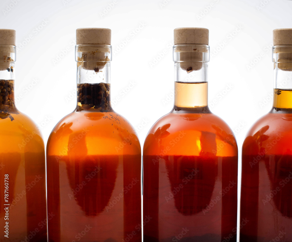Bottles with transparent brown alcoholic drink on a white background. Homemade herbal tincture of herbal moonshine. Elite alcohol. Bottles with transparent brown alcoholic drink on a white background. Homemade herbal tincture of herbal moonshine. Elite alcohol.