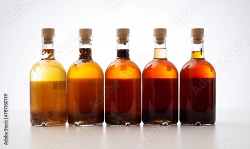 Many bottles with brown transparent alcoholic drink. Homemade tinctures based on natural herbs. Liquor and traditional vodka, collection photo