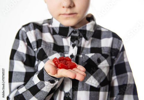 The girl holds red chewable vitamins in the form of bears in her hand. The concept of a multivitamin complex for the health and immunity of children during growth. Vitamin A and B complex, close-up photo