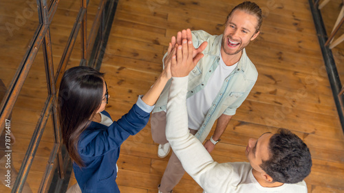 Successful business team is giving high five and smiling while standing in office. Boosting team spirit, deal and agreement on terms and conditions