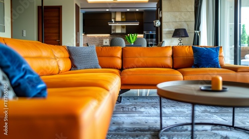 An elegantly designed living room featuring a striking orange leather sofa with complementary blue cushions and modern decor