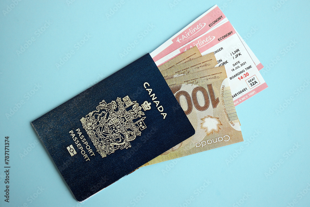 Naklejka premium Canadian passport with money and airline tickets on blue background close up. Tourism and travel concept