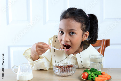 Cute Little Asian Girl Eating Chocolate Cereal