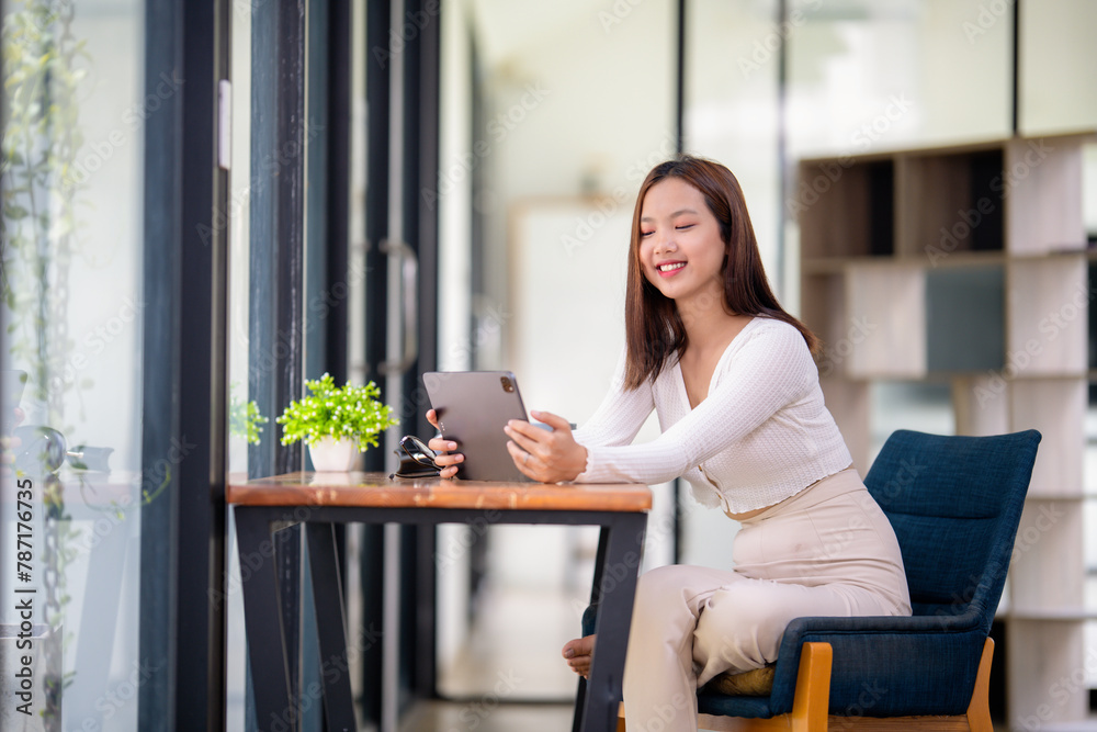 Relaxed young woman smiling as she browses on her tablet, sitting comfortably in a bright modern home. Relaxed young woman smiling as she browses on her tablet, sitting comfortably in a bright modern home.