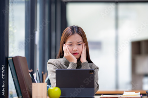 Concentrated young woman studying with a digital tablet, pencil in hand.