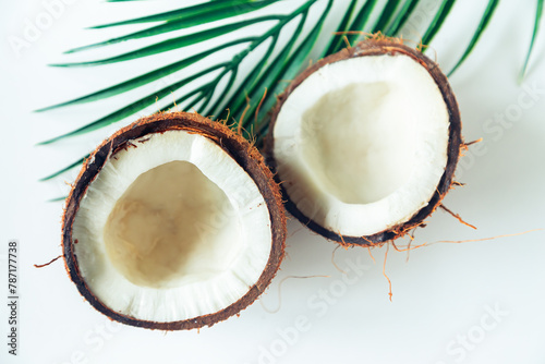 Broken coconut and palm leaf on a white background.