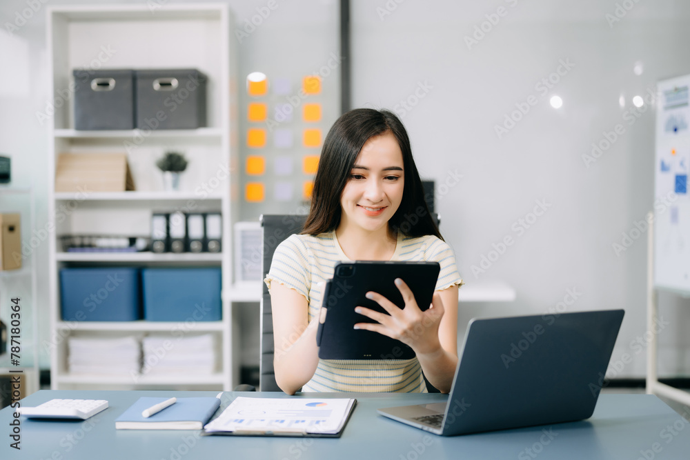Asian businesswoman typing laptop and tablet Placed at the table at the office. Asian businesswoman typing laptop and tablet Placed at the table at the office.