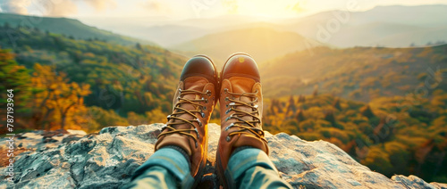 Hiking boots worn in the style of woman on mountain cliff, closeup of shoes and nature background with forest landscape, sunlight. Traveling adventure lifestyle concept banner. photo