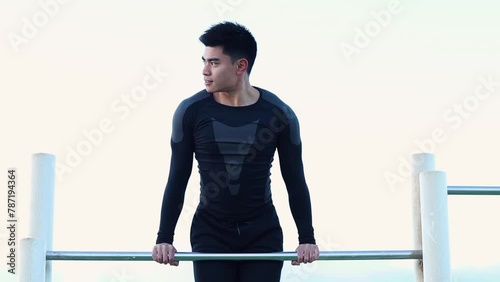 Asian man doing muscle up in outdoors park photo