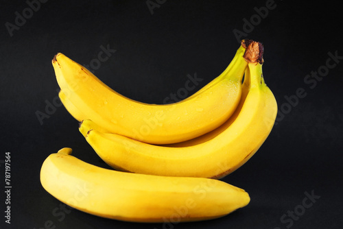 Several ripe yellow bananas on a dark background
