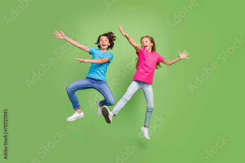 Full length photo of funky positive friends wear t-shirts jumping high having fun isolated green color background