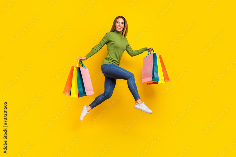 Full size portrait of excited energetic girl hold packages hurry rush fast isolated on yellow color background Full size portrait of excited energetic girl hold packages hurry rush fast isolated on yellow color background