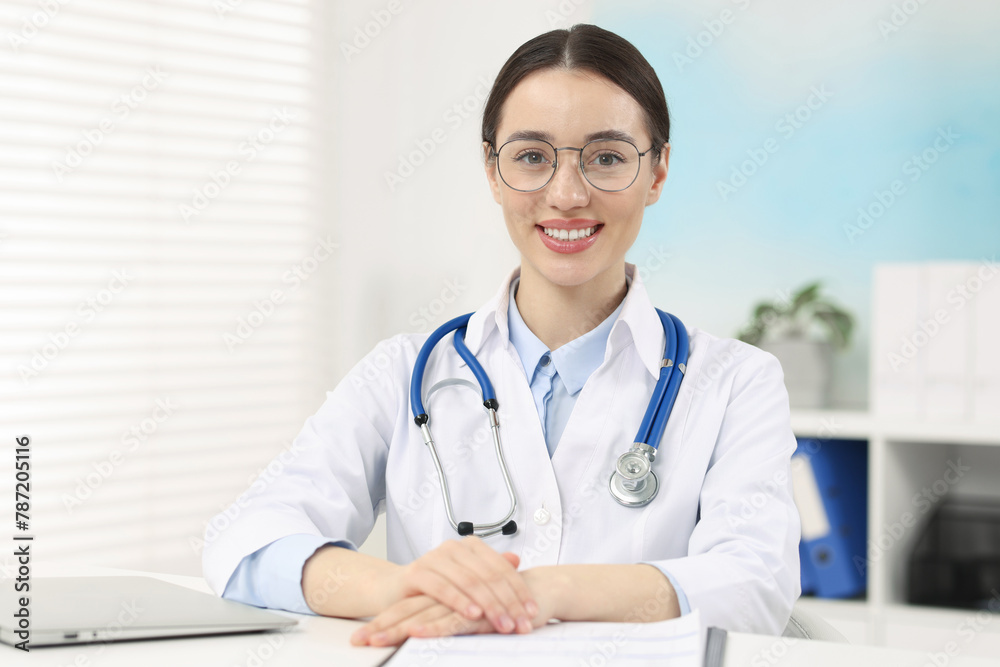 Medical consultant with glasses and stethoscope at table in clinic Medical consultant with glasses and stethoscope at table in clinic