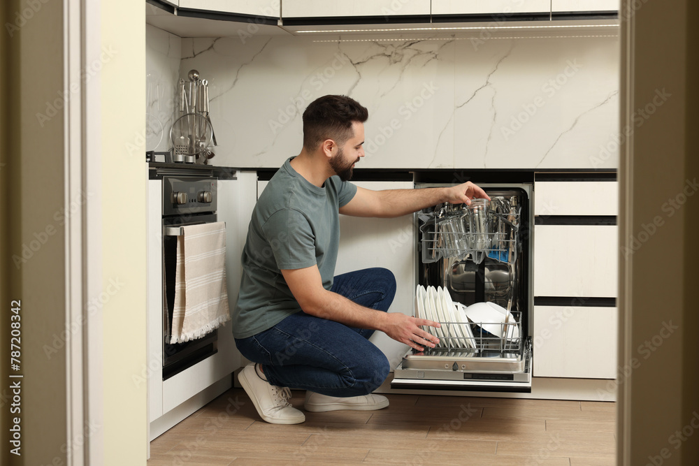 Man loading dishwasher with glasses in kitchen Man loading dishwasher with glasses in kitchen