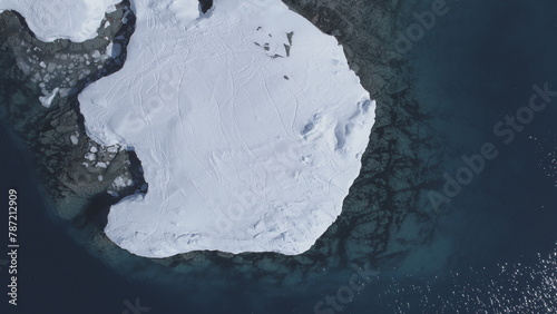Aerial view to Antarctic ocean surface and snow-covered islands. Camera looks down, slowly rises to the horizon. Antarctica icebergs landscape overview. Drone flightin