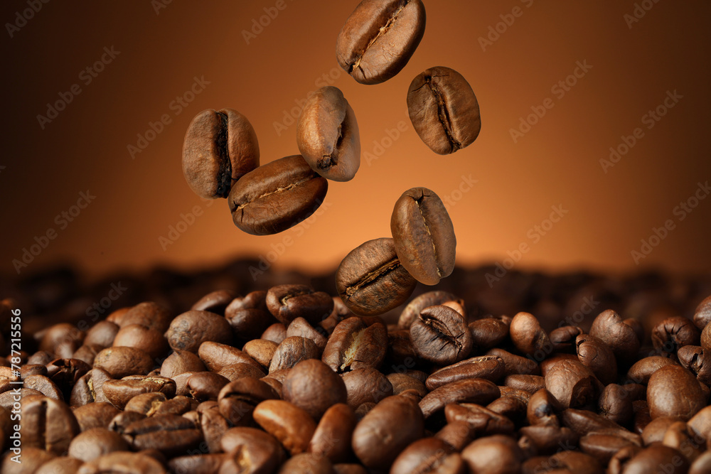 Fototapeta premium Roasted coffee beans falling on heap against brown background, closeup
