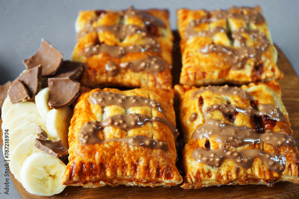 Banana puffs next to sliced ​​banana on a wooden board on a gray background