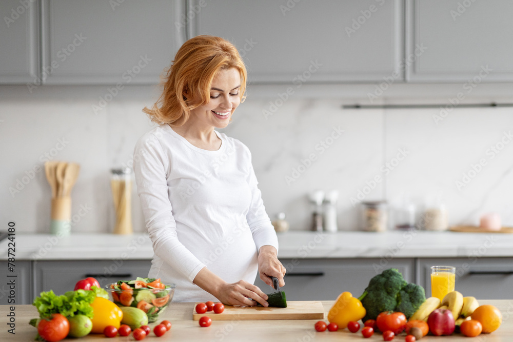 Pregnant woman preparing salad in modern kitchen