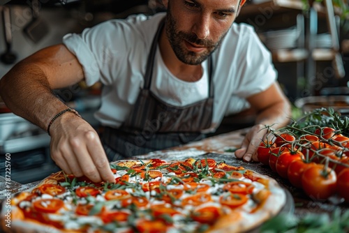 A focused chef delicately places sliced tomatoes on a pizza, showcasing culinary expertise