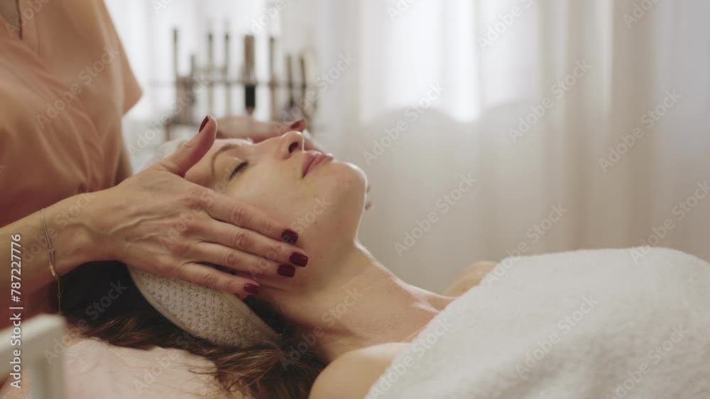 A serene woman receiving a relaxing facial massage at a professional spa salon, captured in a warm and calming atmosphere. A serene woman receiving a relaxing facial massage at a professional spa salon, captured in a warm and calming atmosphere.