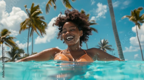 A black woman joyfully swimming in a pool with vibrant turquoise water, surrounded by lush palm trees © Ilia Nesolenyi