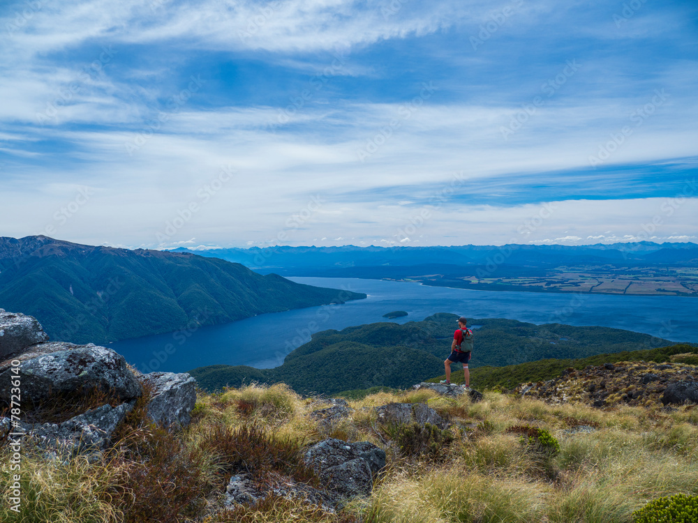 Hiker looking at fjord and mountains in Fiordland National Park Hiker looking at fjord and mountains in Fiordland National Park