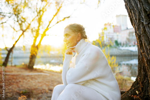 Woman in white sweater sitting by river in autumn photo