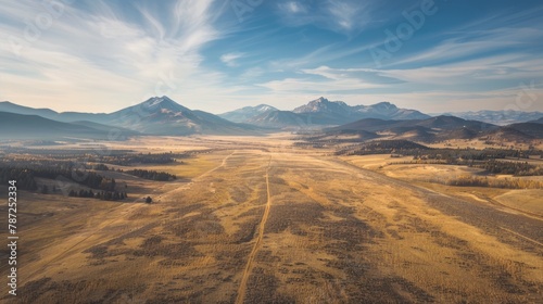 An expansive aerial shot capturing a dirt road winding through mountains in a conservation easement photo