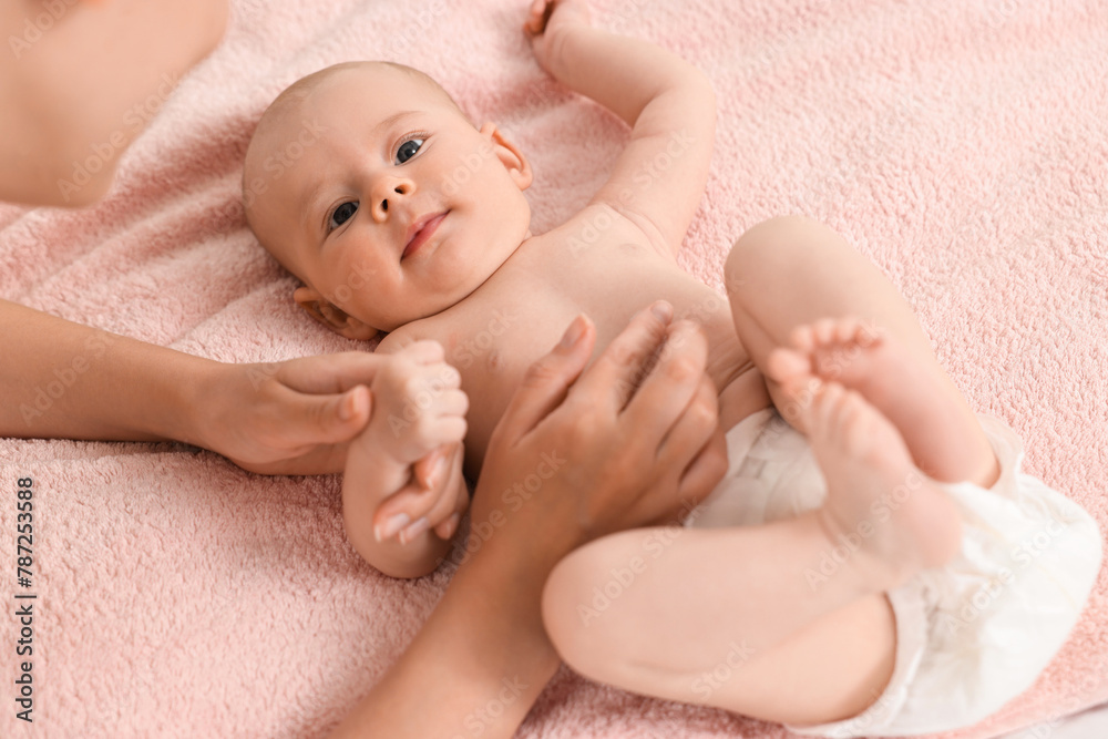 Woman applying body cream onto baby`s skin on bed, closeup Woman applying body cream onto baby`s skin on bed, closeup